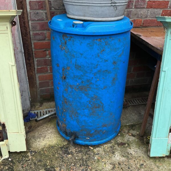 Large metal water butt for garden rainwater harvesting.