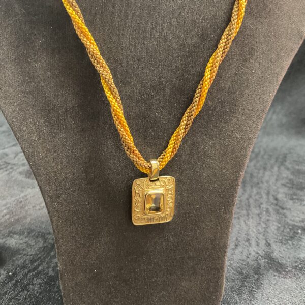 Close-up of the Madeira citrine pendant on a gold rope twist necklace.