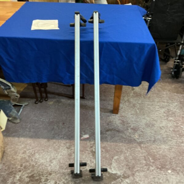 Silver Mercedes Benz roof bars displayed on a blue table.