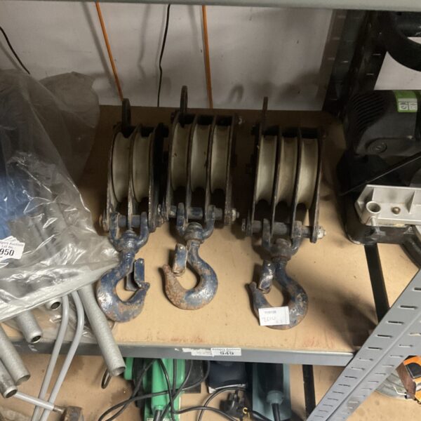 Three vintage metal pulley blocks for industrial lifting.