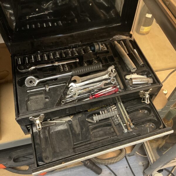 Vintage metal toolbox filled with a collection of hand tools.
