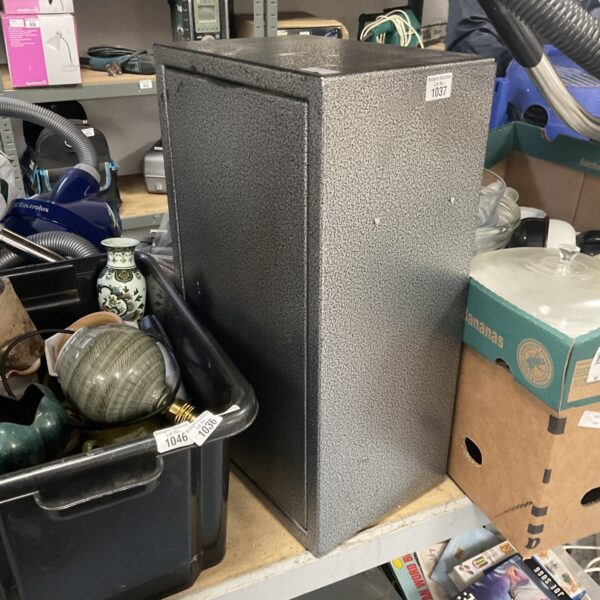 Front view of a metal wall safe with a keyhole.