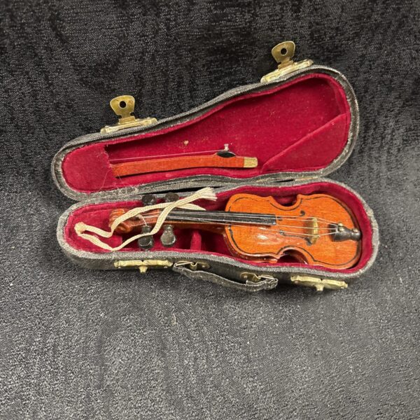 Miniature wooden violin displayed in its velvet-lined case.