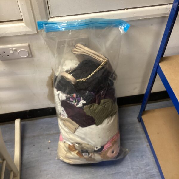 Bagged lot of mixed children's clothing and cuddly toys.