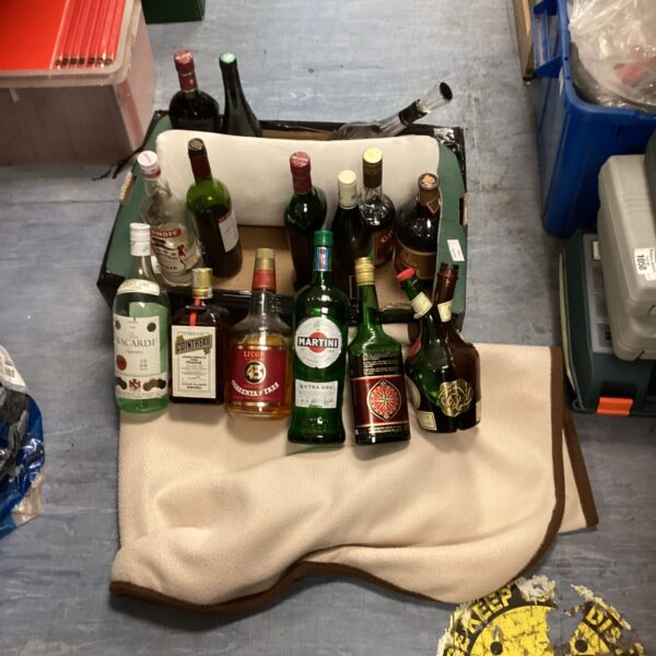 Mixed spirits lot with Martini and Bacardi bottles on a blanket.
