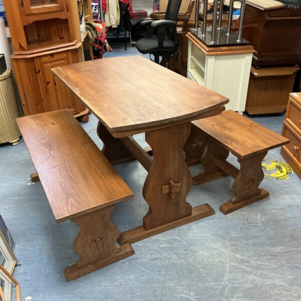 Rustic oak dining table and bench set in a showroom.
