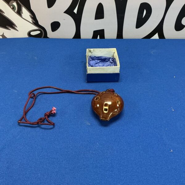 Ceramic pendant ocarina with finger holes and braided cord.