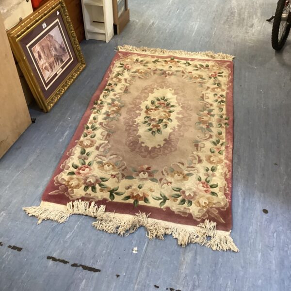 Large pink floral rug with fringed edges, vintage home decor.