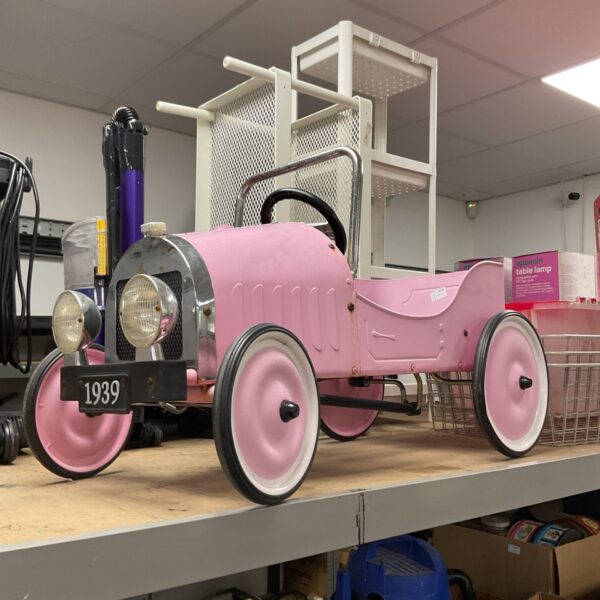 Pink vintage metal ride-on car, classic children's toy.