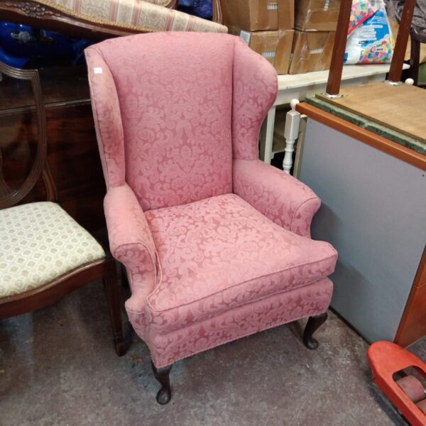 Vintage pink wingback armchair with embossed fabric.