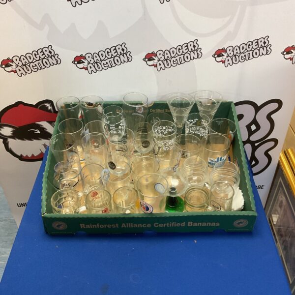 Assorted pint glasses in a tray, a varied glass collection.