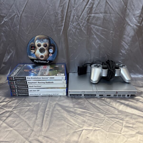 Silver PlayStation 2 Slim console with games and controller.