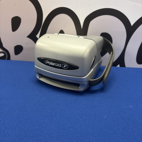 Silver Polaroid 600 instant film camera against a blue backdrop.