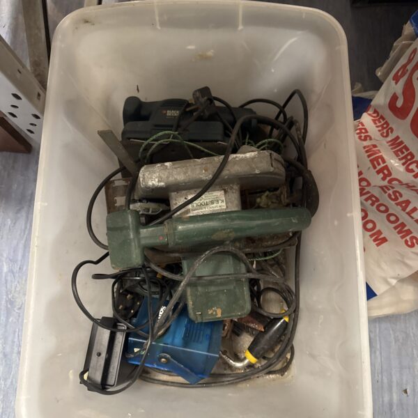 Tray of used power tools including a Black & Decker drill.