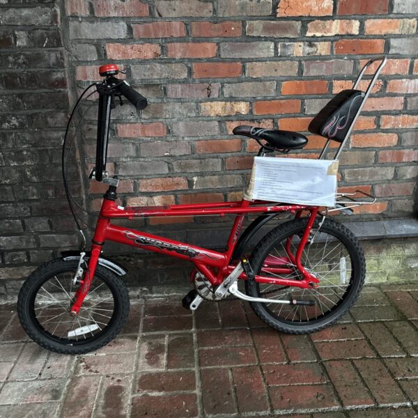 Red Raleigh MK3 Chopper bicycle against brick wall.