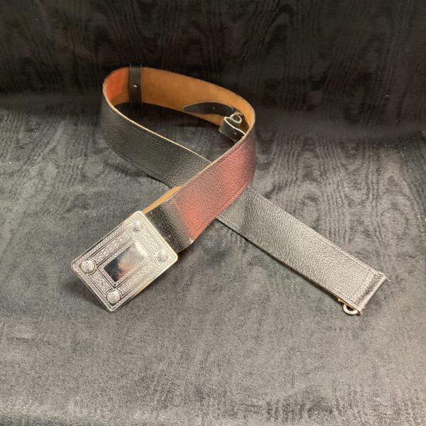 Detailed embossed buckle on a traditional Scottish kilt belt.