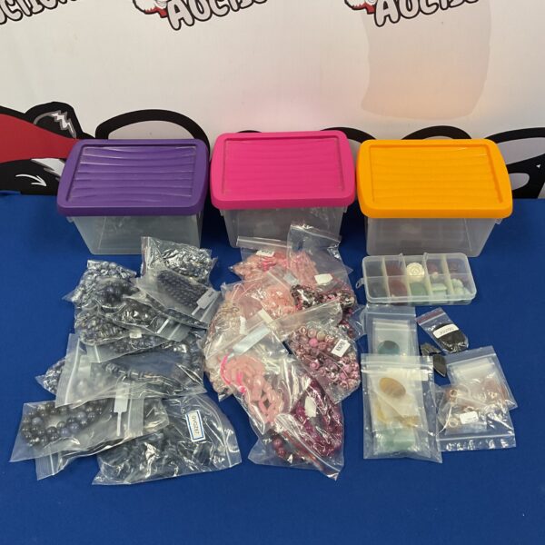 Assorted semi-precious gemstones in plastic storage boxes.
