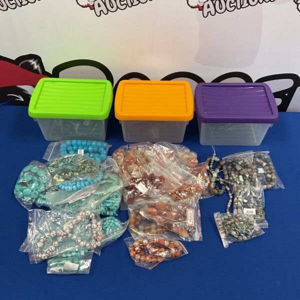 Assorted semi-precious gemstone beads in plastic storage boxes.