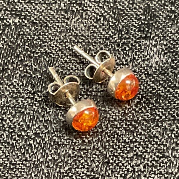 Close-up of silver amber stud earrings with warm tones.