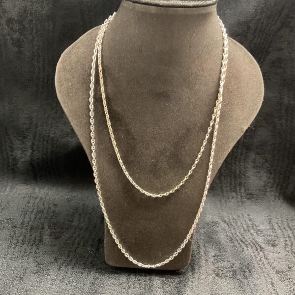 Pair of delicate silver anchor chain necklaces on display.