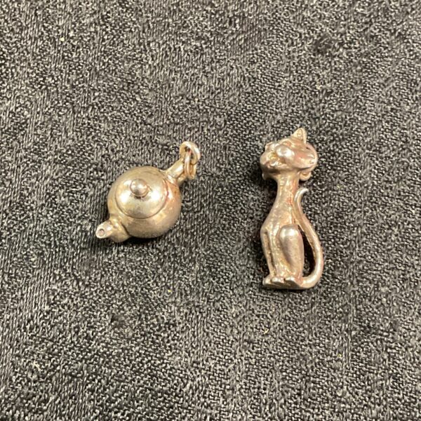 Vintage silver charms featuring a cat and teapot.