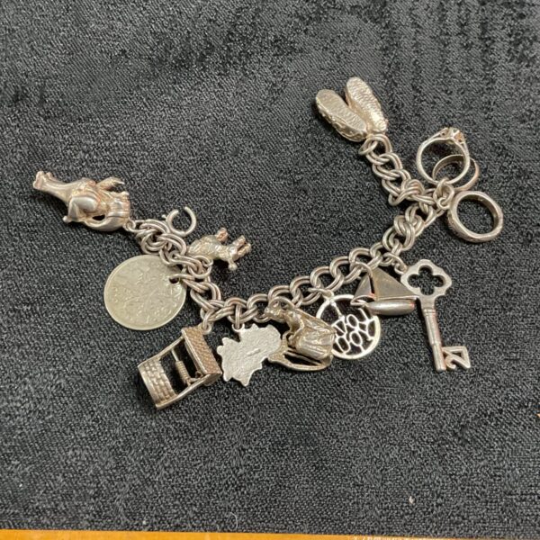 Vintage silver charm bracelet with twelve detailed charms.