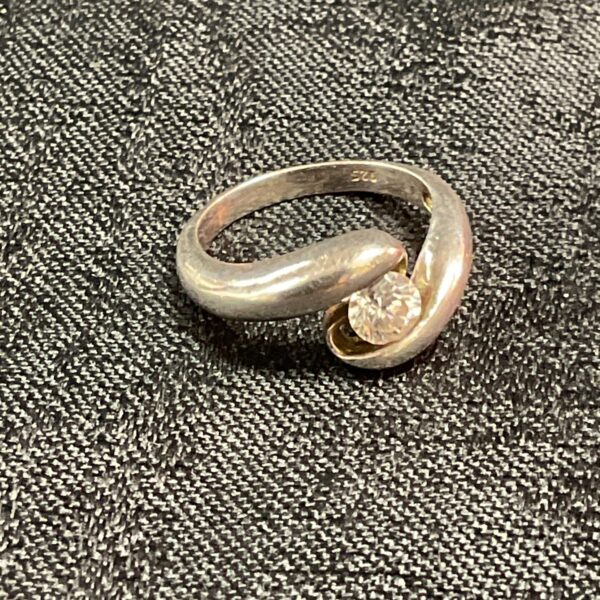 Elegant silver crossover ring with a white stone, size L.