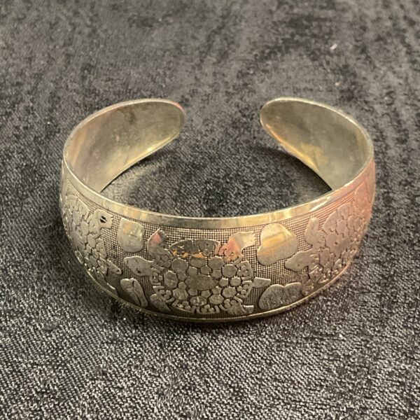 Close-up of a vintage silver turtle bangle with intricate detailing.