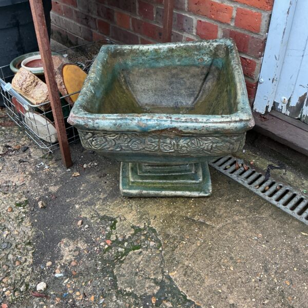 Weathered square garden planter for outdoor plants and decor.