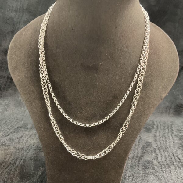 Layered sterling silver necklaces on display, delicate silver chains.