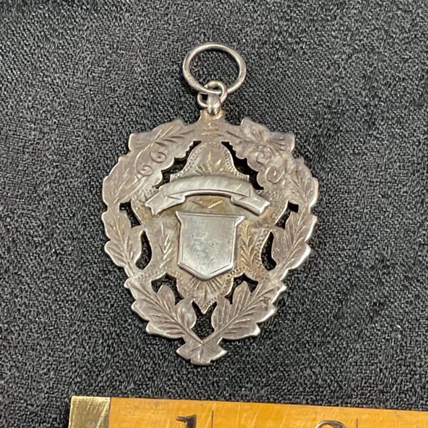 Close-up of vintage sterling silver floral pendant with shield design.