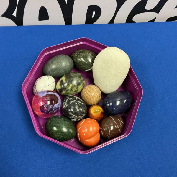 Collection of colourful stone eggs on a tray.
