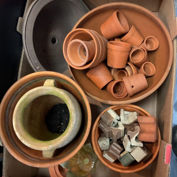 Vintage terracotta pots and stands displayed in a garden setting.