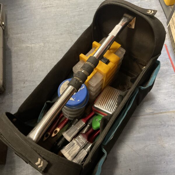 Black tool carry bag filled with assorted DIY and garden tools.