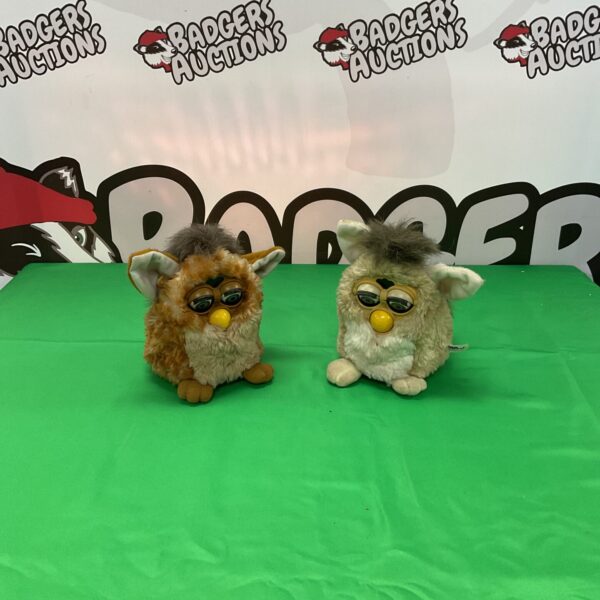 Two vintage Furby toys displayed against a green background.