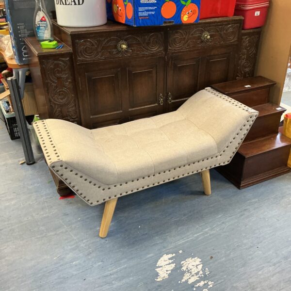 Neutral upholstered ottoman bench with button tufting and tapered legs.