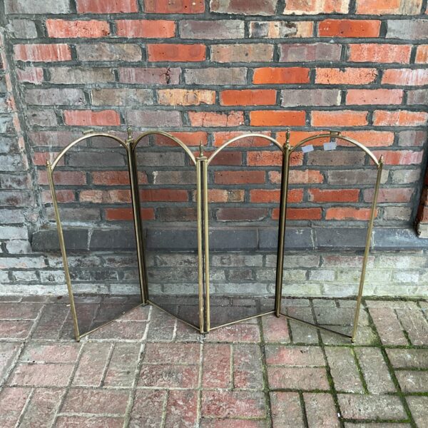 Vintage brass folding fire screen for fireplace safety and style.