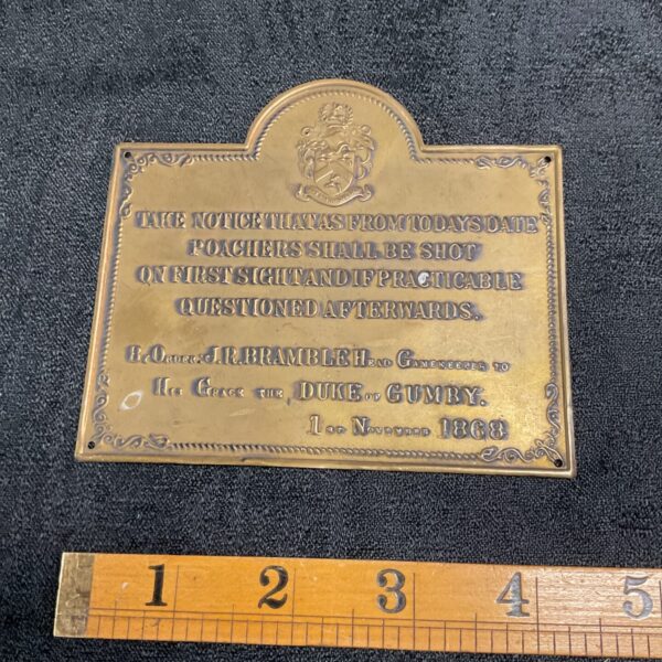 Vintage brass plaque with "Shooters Beware" warning.