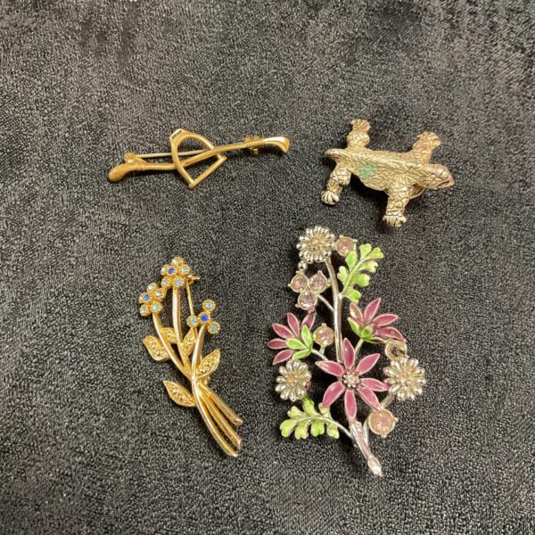 Vintage brooch lot featuring enamel floral pin and other designs.