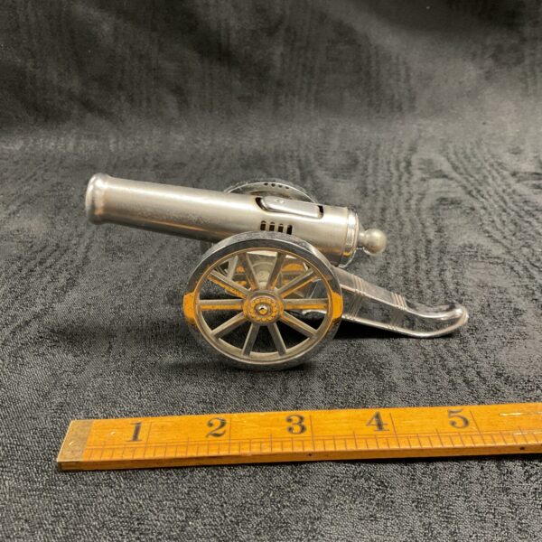 Vintage novelty cannon lighter with ruler for scale.