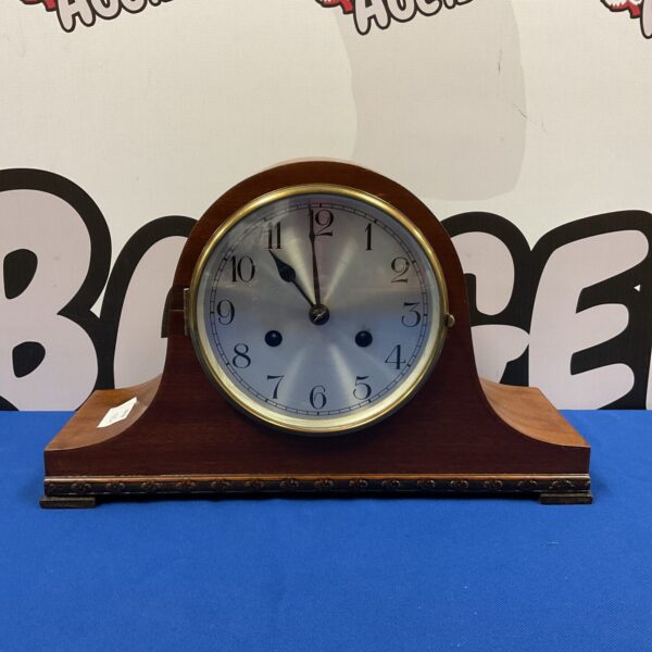 Front view of a vintage DK mantle clock with a circular dial.