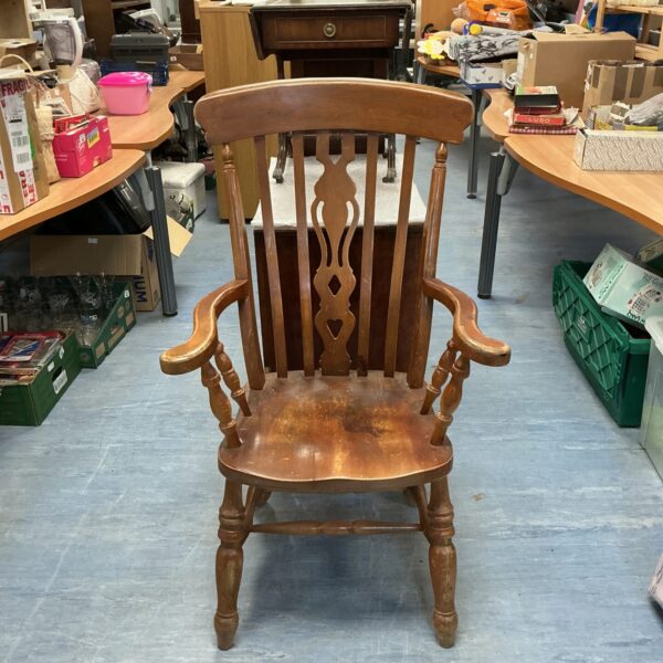 Vintage farmhouse armchair with shaped back and wooden construction.