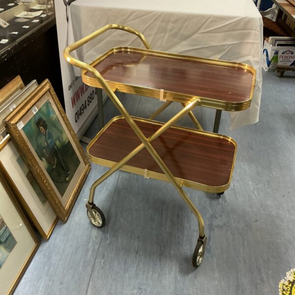 Vintage brass folding bar cart with wooden shelves.