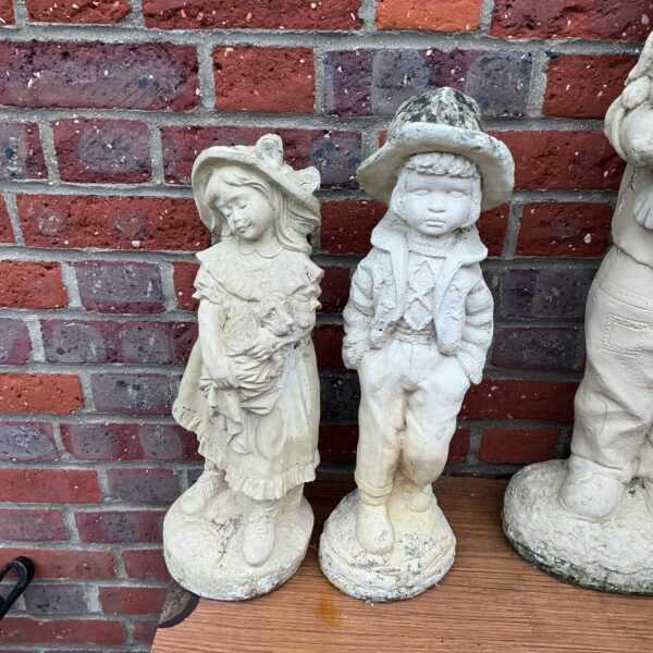 Pair of vintage concrete garden statues in a garden setting.