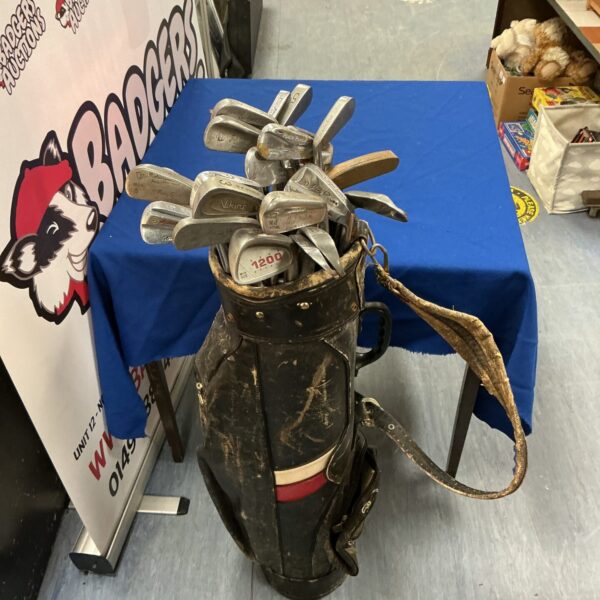 Vintage golf clubs in a worn leather bag, antique sporting equipment.