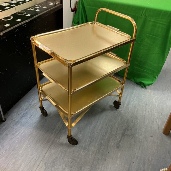 Vintage gold metal drinks trolley with three tiers.