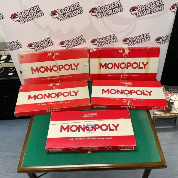Lot of five vintage Monopoly board games displayed on a table.