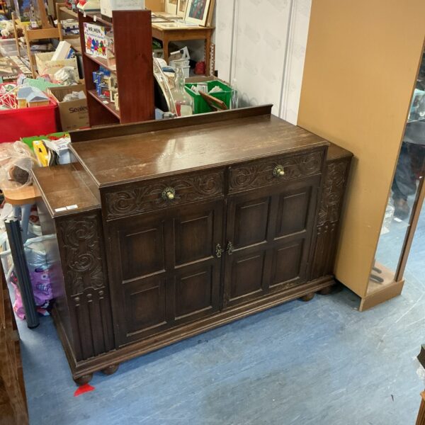 Front view of a vintage carved oak sideboard with cupboards.