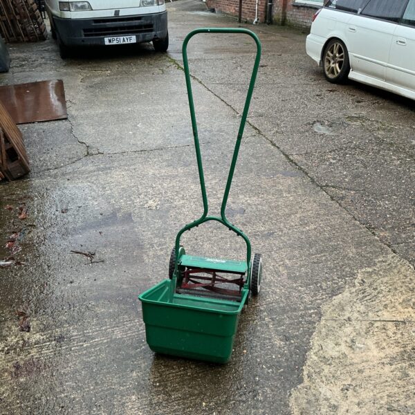 Vintage Qualcast push mower in a garden setting.