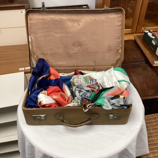 Vintage suitcase filled with colourful silk scarves, retro fashion.